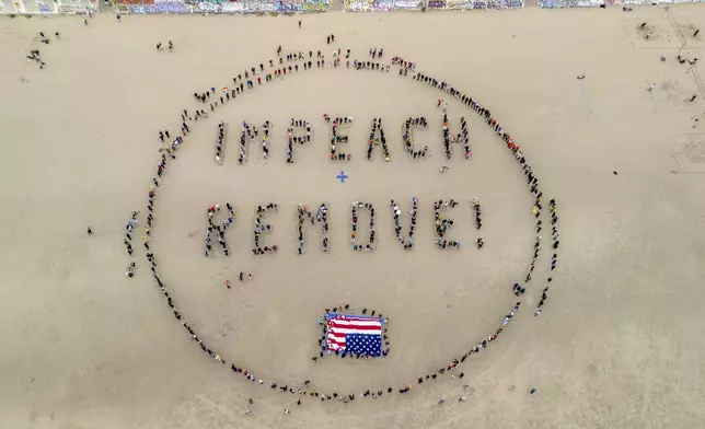 Protesters form a "Impeach &amp; Remove" human banner on Ocean Beach during a protest against U.S. President Donald Trump, in San Francisco, Saturday, April 19, 2025. (Stephen Lam/San Francisco Chronicle via AP)