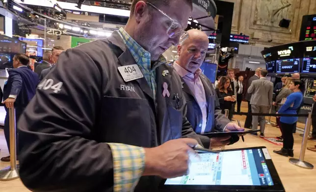 Traders Ryan Falvey, left, and Patrick Casey work on the floor of the New York Stock Exchange, Thursday, April 10, 2025. (AP Photo/Richard Drew)