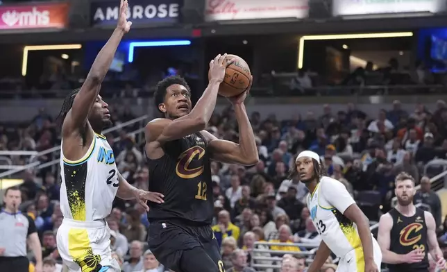 Cleveland Cavaliers forward De'Andre Hunter (12) shoots in front of Indiana Pacers forward Aaron Nesmith (23) during the first half of an NBA basketball game in Indianapolis, Thursday, April 10, 2025. (AP Photo/Michael Conroy)