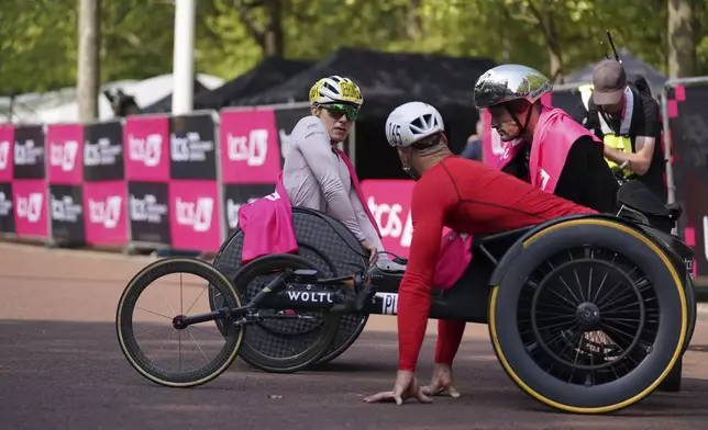 Marcel Hug of Switzerland, right, winner of the men's wheelchair race and Jetze Plat of the Netherland's who placed third in the men's race speak to Catherine Debrunner of Switzerland who won the women's wheelchair race near the finish line at the London Marathon, Sunday, April 27, 2025. (AP Photo/Alberto Pezzali)