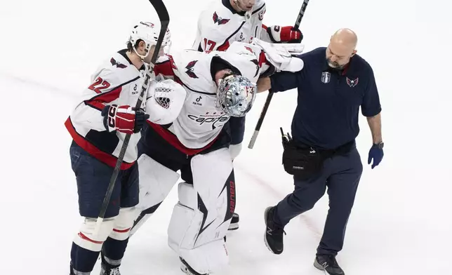 Washington Capitals goaltender Logan Thompson, center front, is helped off the ice during the third period of Game 3 of a first-round NHL hockey playoff series against the Montreal Capitalls in Montreal, Friday, April 25, 2025. (Christinne Muschi/The Canadian Press via AP)