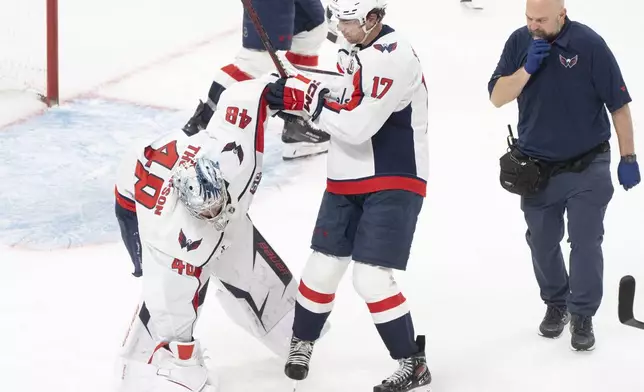 Washington Capitals goaltender Logan Thompson (48) stumbles as he is helped off the ice by teammate Dylan Strome (17) during the third period of Game 3 of a first-round NHL hockey playoff series against the Montreal Canadiens in Montreal, Friday, April 25, 2025. (Christinne Muschi/The Canadian Press via AP