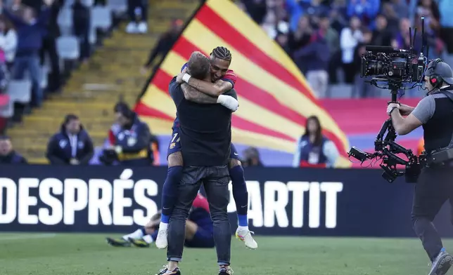 Barcelona's head coach Hansi Flick celebrates with Barcelona's Raphinha at the end of the Spanish La Liga soccer match between Barcelona and Celta de Vigo at the Lluis Companys Olympic stadium in Barcelona, Spain, Saturday, April 19, 2025. (AP Photo/Joan Monfort)