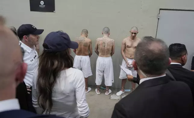 Shackled prisoners stand against a wall as Homeland Security Secretary Kristi Noem tours the Terrorist Confinement Center in Tecoluca, Salvador, Wednesday, March 26, 2025. (AP Photo/Alex Brandon)