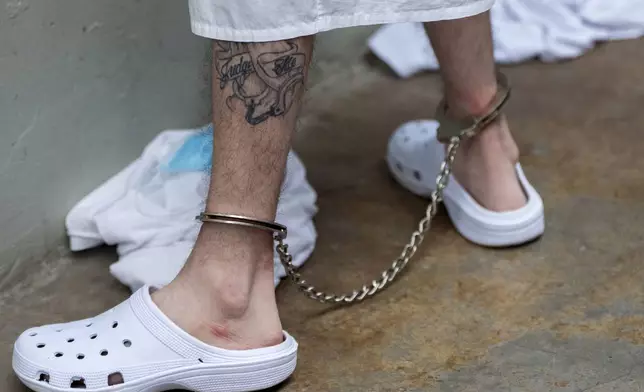 A prisoner with a tattoo with leg irons on stands as Homeland Security Secretary Kristi Noem tours the Terrorist Confinement Center in Tecoluca, El Salvador, Wednesday, March 26, 2025. (AP Photo/Alex Brandon)