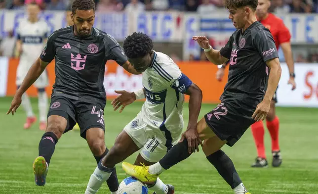 Vancouver Whitecaps' Emmanuel Sabbi, center, is tackled by Inter Miami's Noah Allen, right, and Yannick Bright, left, during the second half of a CONCACAF Champions Cup semifinal soccer match, in Vancouver, British Columbia, Thursday, April 24, 2025. (Christopher Morris/The Canadian Press via AP)