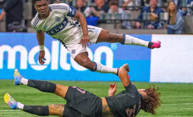 Vancouver Whitecaps' Emmanuel Sabbi, top, jumps over Inter Miami's Maximiliano Falcon during the second half of a CONCACAF Champions Cup semifinal soccer match, in Vancouver, British Columbia, Thursday, April 24, 2025. (Christopher Morris/The Canadian Press via AP)