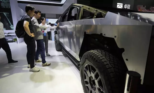 Visitors look at a bare-bones version of Tesla's Cybertruck with devices from AOD Technology, which makes domain control units that process various commands such as opening doors and controlling running boards on SUVs, displayed at the Shanghai auto show on Thursday, April 24, 2025. (AP Photo/Ng Han Guan)
