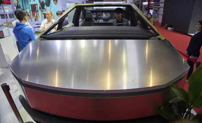 Visitors look at a bare-bones version of Tesla's Cybertruck with devices from AOD Technology, which makes domain control units that process various commands such as opening doors and controlling running boards on SUVs, displayed at the Shanghai auto show on Thursday, April 24, 2025. (AP Photo/Ng Han Guan)