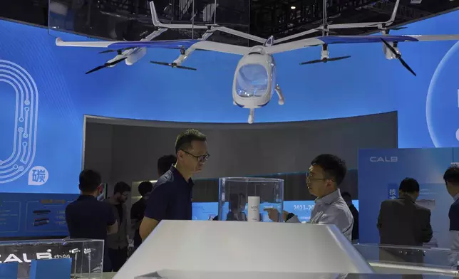 Visitors look at a model of a flying vehicle at the booth for Chinese lithium battery manufacturer CALB during the Shanghai auto show on Thursday, April 24, 2025. (AP Photo/Ng Han Guan)