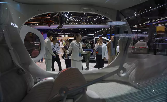 A worker introduces GOVY Air Car from GAC Group displayed at the Shanghai auto show on Thursday, April 24, 2025. (AP Photo/Ng Han Guan)