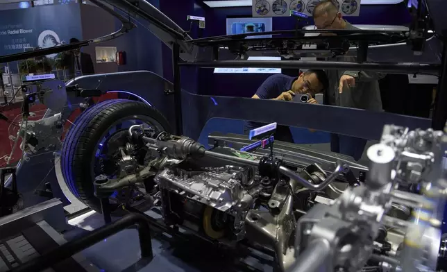 Visitors look at auto components made by Japanese auto parts manufacturer Aisin displayed at the Shanghai auto show on Thursday, April 24, 2025. (AP Photo/Ng Han Guan)
