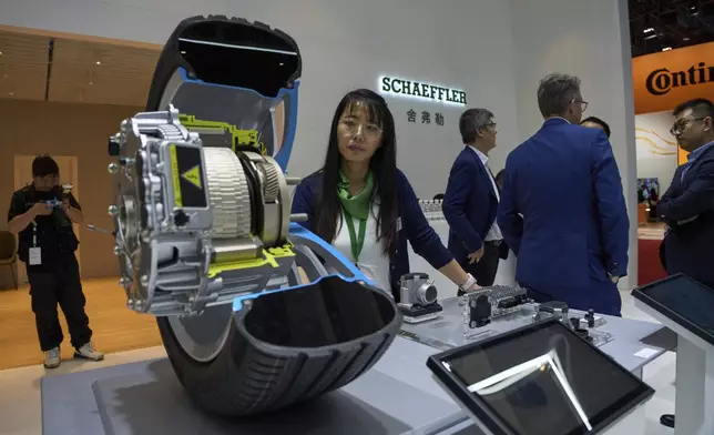 A worker stands near a cut out of a wheel at the booth for Schaeffler at the Shanghai auto show on Thursday, April 24, 2025. (AP Photo/Ng Han Guan)