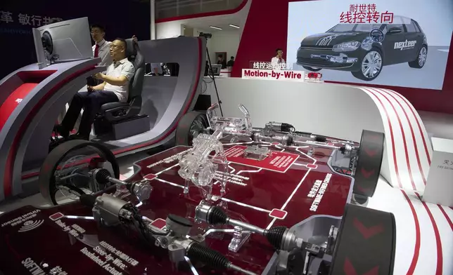A visitor tries out a driving platform at the booth for auto parts manufacturer Nexteer Automotive during the Shanghai auto show on Thursday, April 24, 2025. (AP Photo/Ng Han Guan)
