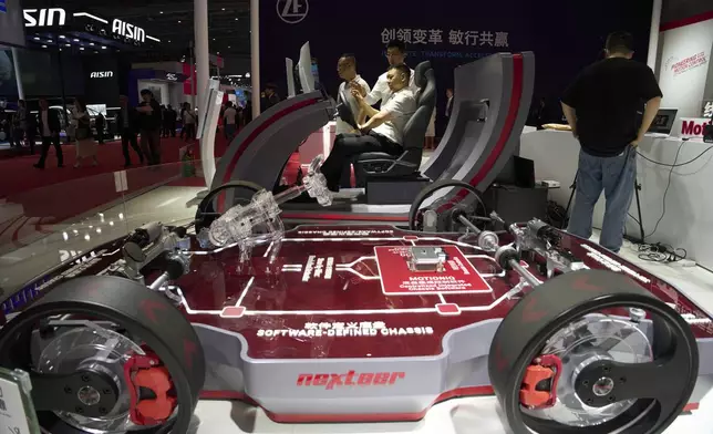 A visitor tries out a driving platform at the booth for auto parts manufacturer Nexteer Automotive during the Shanghai auto show on Thursday, April 24, 2025. (AP Photo/Ng Han Guan)