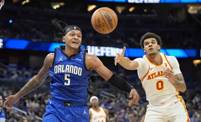 Orlando Magic forward Paolo Banchero (5) and Atlanta Hawks forward Dominick Barlow (0) go after a rebound during the first half of an NBA play-in tournament basketball game, Tuesday, April 15, 2025, in Orlando, Fla. (AP Photo/John Raoux)
