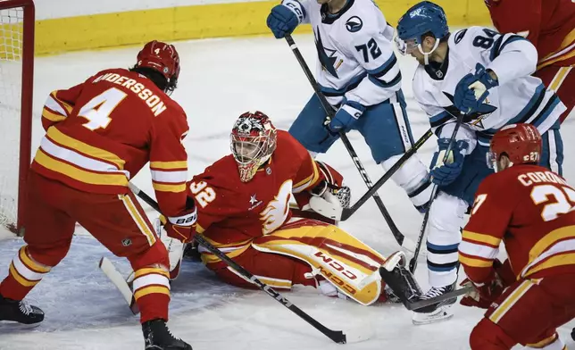 San Jose Sharks' Jan Rutta (84) scores on Calgary Flames goalie Dustin Wolf (32) during second period NHL hockey action in Calgary on Sunday, April 13, 2025. (Jeff McIntosh/The Canadian Press via AP)