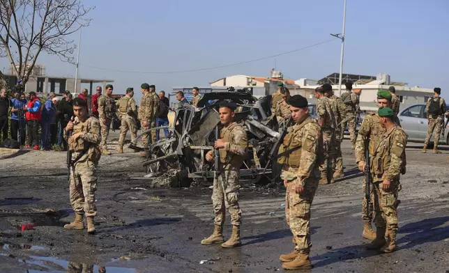 Lebanese army soldiers gather near a charred car that was hit by an Israeli strike, in the southern coastal town of Ghazieh, Lebanon, Friday, April 18, 2025. (AP Photo/Mohammed Zaatari)
