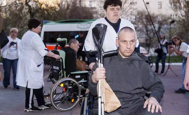 A medical worker uses a wheelchair to move an injured Ukrainian soldier from an ambulance after returning from captivity in a POW exchange in Ukraine, on Saturday, April. 19, 2025. (AP Photo/Evgeniy Maloletka)