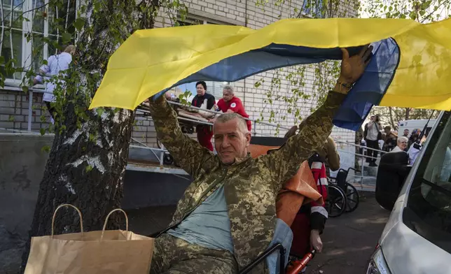 An injured Ukrainian soldier waves a national flag after returning from captivity in a POW exchange in Ukraine, on Saturday, April. 19, 2025. (AP Photo/Evgeniy Maloletka)
