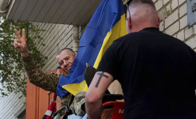 An injured Ukrainian soldier makes a victory sign after returning from captivity in a POW exchange in Ukraine, on Saturday, April. 19, 2025. (AP Photo/Evgeniy Maloletka)
