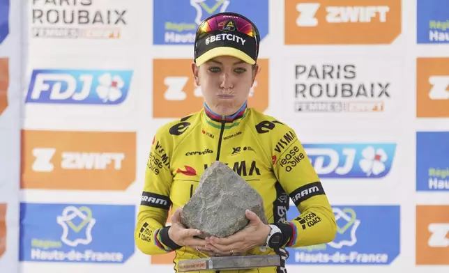 Pauline Ferrand Prevot, of France, lifts the cobblestone trophy after winning the Paris-Roubaix cycling race in Roubaix, France, Saturday, April 12, 2025. (AP Photo/Thibault Camus)