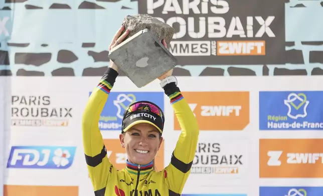 Pauline Ferrand Prevot, of France, lifts the cobblestone trophy after winning the Paris-Roubaix cycling race in Roubaix, France, Saturday, April 12, 2025. (AP Photo/Thibault Camus)