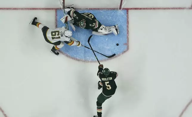 Minnesota Wild goaltender Filip Gustavsson (32) and defenseman Jake Middleton (5) defend against a shot attempt by Vegas Golden Knights right wing Mark Stone (61) during the third period of Game 3 of a first-round NHL hockey playoff series Thursday, April 24, 2025, in St. Paul, Minn. (AP Photo/Abbie Parr)