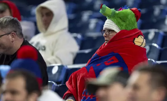 Philadelphia Phillies fans look on while bundled up due to the cold windy weather during the ninth inning of a baseball game against the San Francisco Giants, Wednesday, April 16, 2025, in Philadelphia. (AP Photo/Chris Szagola)