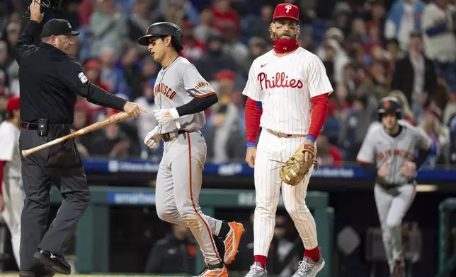Philadelphia Phillies first baseman Bryce Harper, right, reacts as San Francisco Giants' Jung Hoo Lee, center scores a run on a throwing error during the fifth inning of a baseball game, Wednesday, April 16, 2025, in Philadelphia. (AP Photo/Chris Szagola)