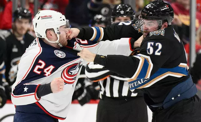 Washington Capitals defenseman Dylan McIlrath (52) and Columbus Blue Jackets right wing Mathieu Olivier (24) fight during the first period of an NHL hockey game, Sunday, April 13, 2025, in Washington. (AP Photo/Nick Wass)