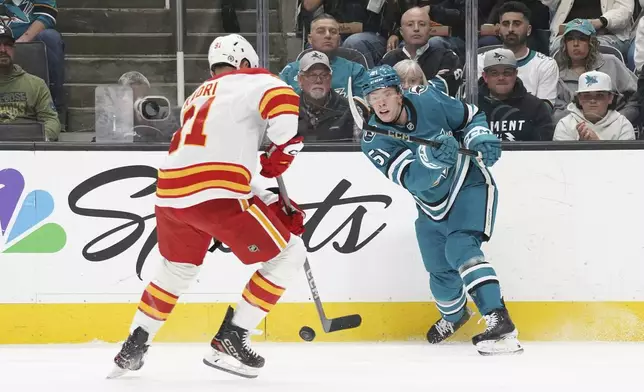 Calgary Flames center Nazem Kadri, left, fights for the puck against San Jose Sharks right wing Collin Graf (51) during the first period of an NHL hockey game in San Jose, Calif., Monday, April 7, 2025. (AP Photo/Minh Connors)