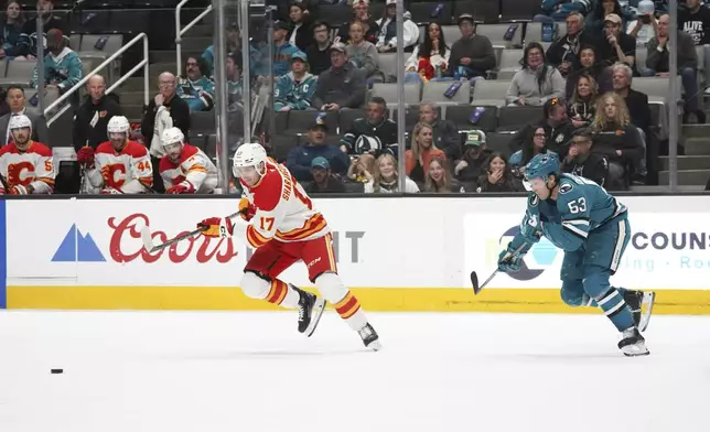 Calgary Flames center Yegor Sharangovich (17) and San Jose Sharks center Ty Dellandrea (53) go for the puck during the first period of an NHL hockey game in San Jose, Calif., April 7, 2025. (AP Photo/Minh Connors)