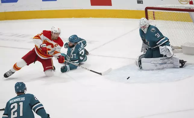Calgary Flames center Mikael Backlund, top left, attempts a shot as San Jose Sharks players, from left, Alexander Wennberg, Timothy Liljegren and Georgi Romanov defend during the second period of an NHL hockey game in San Jose, Calif., Monday, April 7, 2025. (AP Photo/Minh Connors)