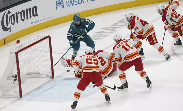 San Jose Sharks center Will Smith attempts a shot on goal around a group of Calgary Flames players during the second period of an NHL hockey game in San Jose, Calif., Monday, April 7, 2025. (AP Photo/Minh Connors)