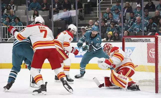 San Jose Sharks right wing Barclay Goodrow (23) attempts a pass between a group of Calgary Flames players during the first period of an NHL hockey game in San Jose, Calif., April 7, 2025. (AP Photo/Minh Connors)