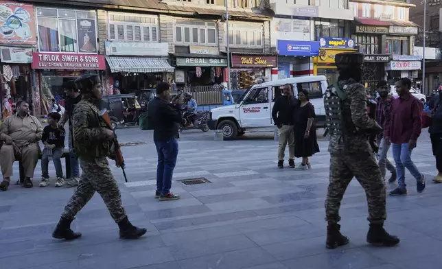Indian paramilitary soldiers patrol as tourists take pictures at a busy market in Srinagar, Indian controlled Kashmir, Tuesday, April 29, 2025. (AP Photo/Mukhtar Khan)