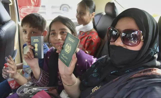 Pakistani national Khalida Hanif, right, and her Indian children display their passports on their return from Pakistan at the Attari-Wagah border between India and Pakistan, near Amritsar, India, Tuesday, April 29, 2025. (AP Photo/Prabhjot Gill)