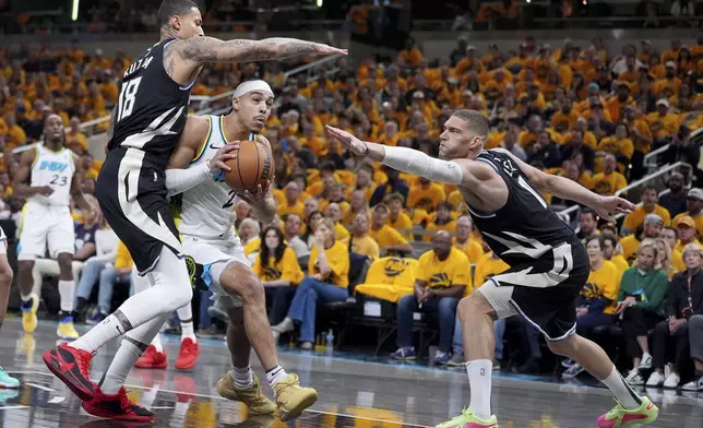 Indiana Pacers' Andrew Nembhard, center, heads to the basket past Milwaukee Bucks' Kyle Kuzma (18) and Brook Lopez, right, during the first half of a first-round NBA basketball playoff game, Saturday, April 19, 2025, in Indianapolis. (AP Photo/Michael Conroy)