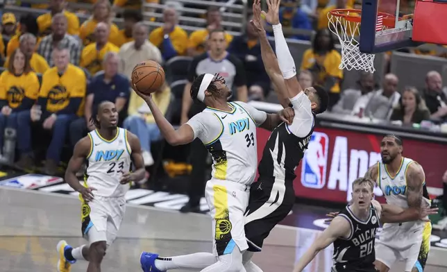Indiana Pacers' Myles Turner (33) heads to the basket as Milwaukee Bucks' Giannis Antetokounmpo defends during the second half of a first-round NBA basketball playoff game, Saturday, April 19, 2025, in Indianapolis. (AP Photo/Michael Conroy)