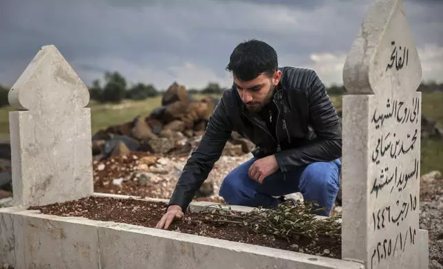 Salah Swed, 28, visits the grave of his brother Mohammed, who was killed while trying to dismantle a landmine, in their village of Kafr Nabl, south of Idlib, Syria, Monday, April 14, 2025. (AP Photo/Ghaith Alsayed)