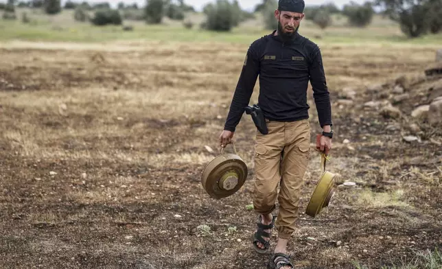 Members of the ministry of defence clear landmines left behind by the Syrian army during the war, in agricultural land south of Idlib, Syria, Sunday, April 13, 2025. (AP Photo/Ghaith Alsayed)