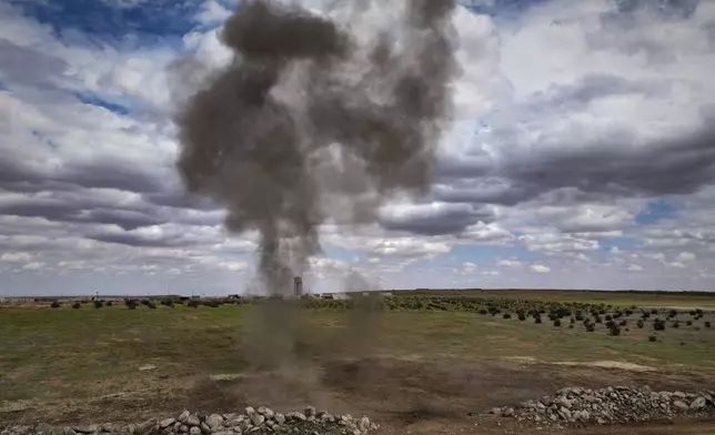Smoke billows as a landmine is detonated during a ministry of defence operation to clear explosives left behind by the Syrian army during the war, in agricultural land south of Idlib, Syria, Sunday, April 13, 2025. (AP Photo/Ghaith Alsayed)