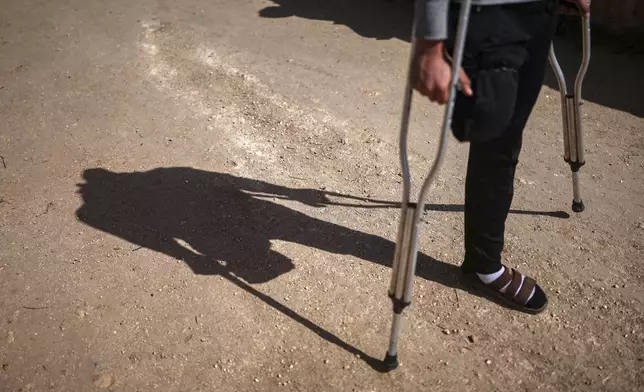 Suleiman Khalil, 21, who lost his leg in a landmine explosion while harvesting olives with his friends in a field, walks outside his home in the village of Qaminas, east of Idlib, Syria, Wednesday, April 9, 2025. (AP Photo/Ghaith Alsayed)