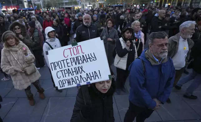 A woman holds a banner reads: "Stop, expulsion of foreign citizens!" during a protest denouncing the expulsion and entry bans of dozens of foreign citizens recently due to alleged security risks for the Balkan country, in Belgrade, Serbia, Thursday, April 10, 2025. (AP Photo/Darko Vojinovic)