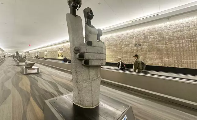 People walk by a Zimbabwean sculpture piece at Hartsfield-Jackson Atlanta International Airport, Friday, Feb. 28, 2025, in Atlanta. (AP Photo/Ravi Nessman)
