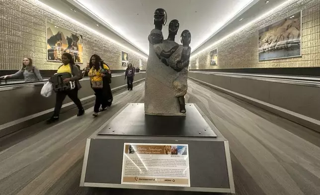 People walk by a Zimbabwean sculpture piece at Hartsfield-Jackson Atlanta International Airport, Friday, Feb. 28, 2025, in Atlanta. (AP Photo/Ravi Nessman)