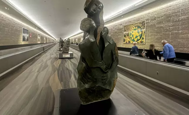 People walk by Zimbabwean sculpture piece at Hartsfield-Jackson Atlanta International Airport, Friday, Feb. 28, 2025, in Atlanta. (AP Photo/Ravi Nessman)