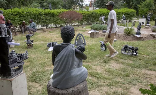 People walk past sculptures that will be part of an upcoming exhibition at Oxford University aiming to contextualize the legacy of British imperialist Cecil John Rhodes, at the Chitungwiza Arts Centre near Harare, Zimbabwe, Tuesday, March 4, 2025. (AP Photo/Aaron Ufumeli)