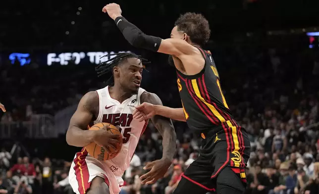 Miami Heat guard Davion Mitchell (45) dribbles against Atlanta Hawks forward Jalen Johnson (1) in overtime of an NBA play-in tournament basketball game against the Friday, April 18, 2025, in Atlanta. (AP Photo/Brynn Anderson)